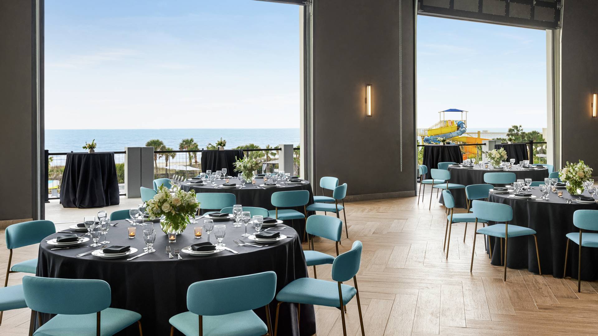 Beautiful on-site ballroom featuring banquet setup with large roll up doors open to terrace and ocean view