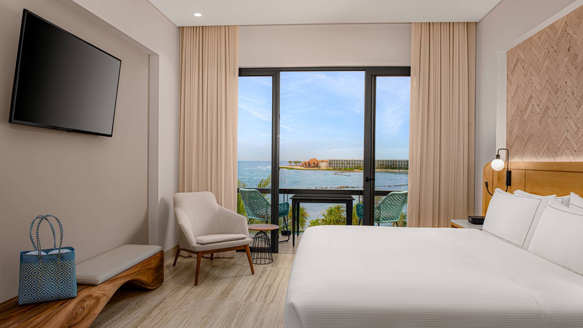 Habitación con cama grande, televisor de alta definición y vista al mar desde el balcón