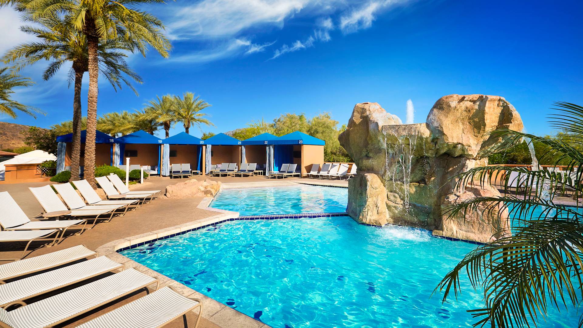 Outdoor Pool Area with a Cascade, Cabanas and Lounge Chairs