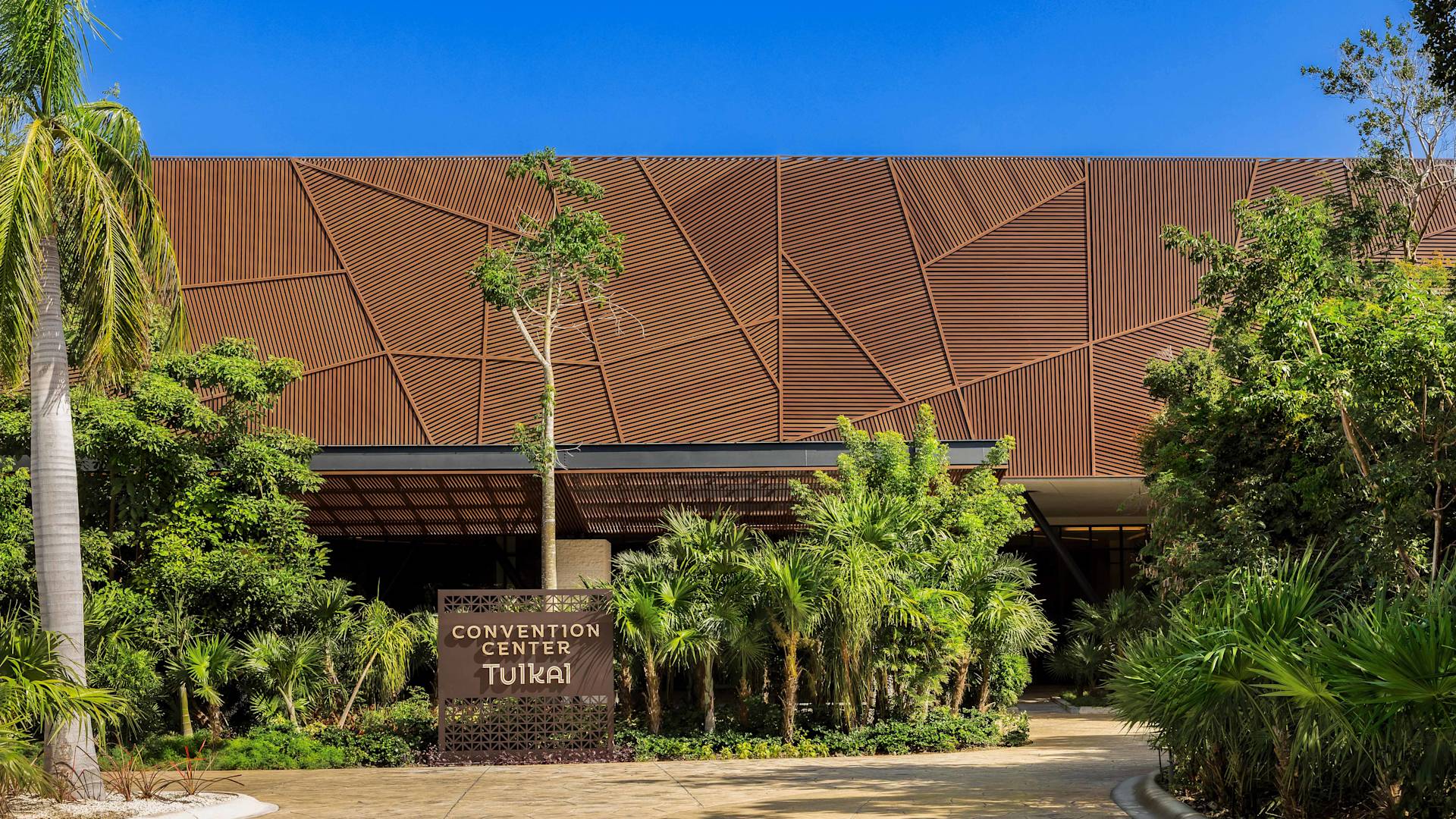 Tulkai-kokouskeskuksen rakennus ulkopuolelta, kylteistä ja palmuista