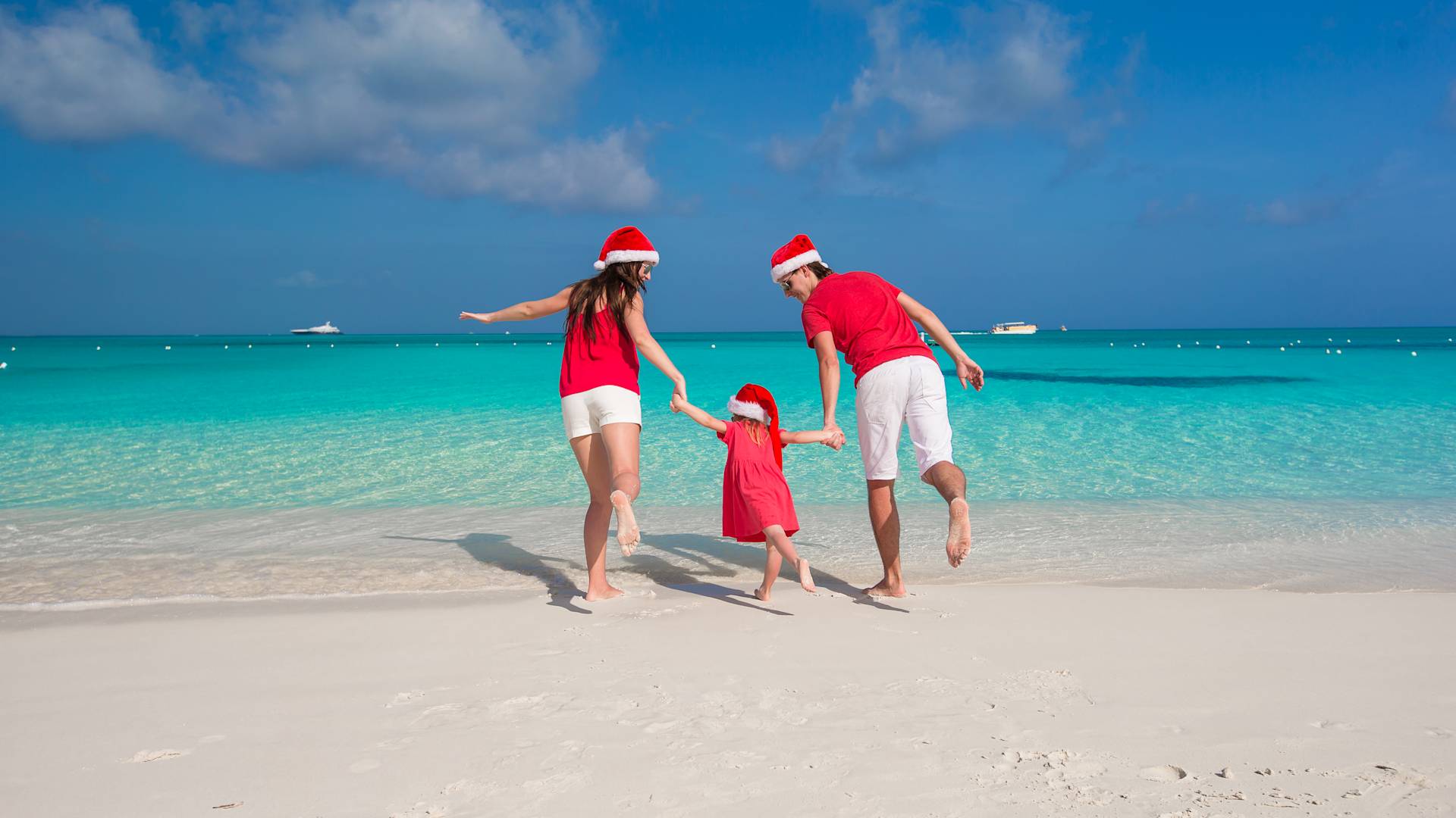 famille sur la plage portant un chapeau Santa