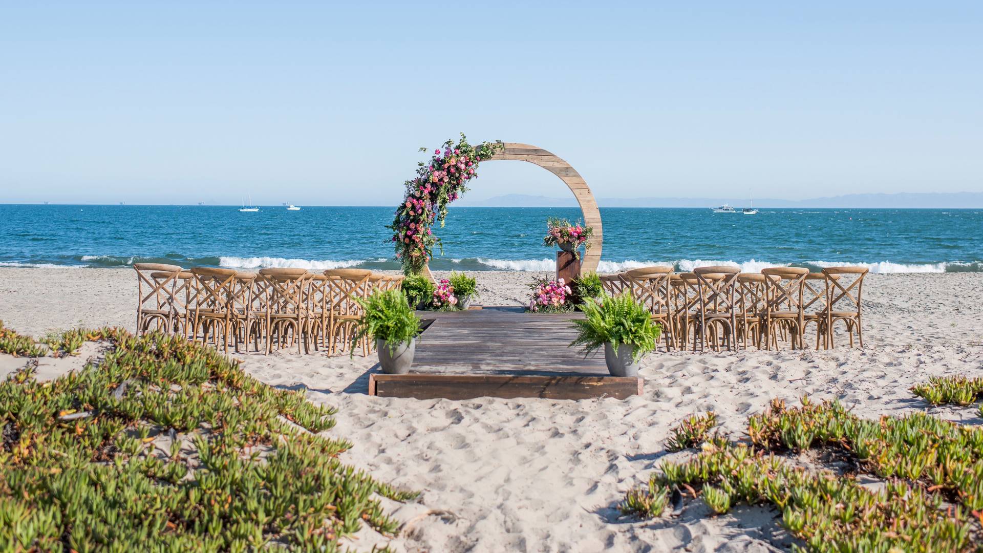 Beach view, with wedding set up featuring chairs and flowers