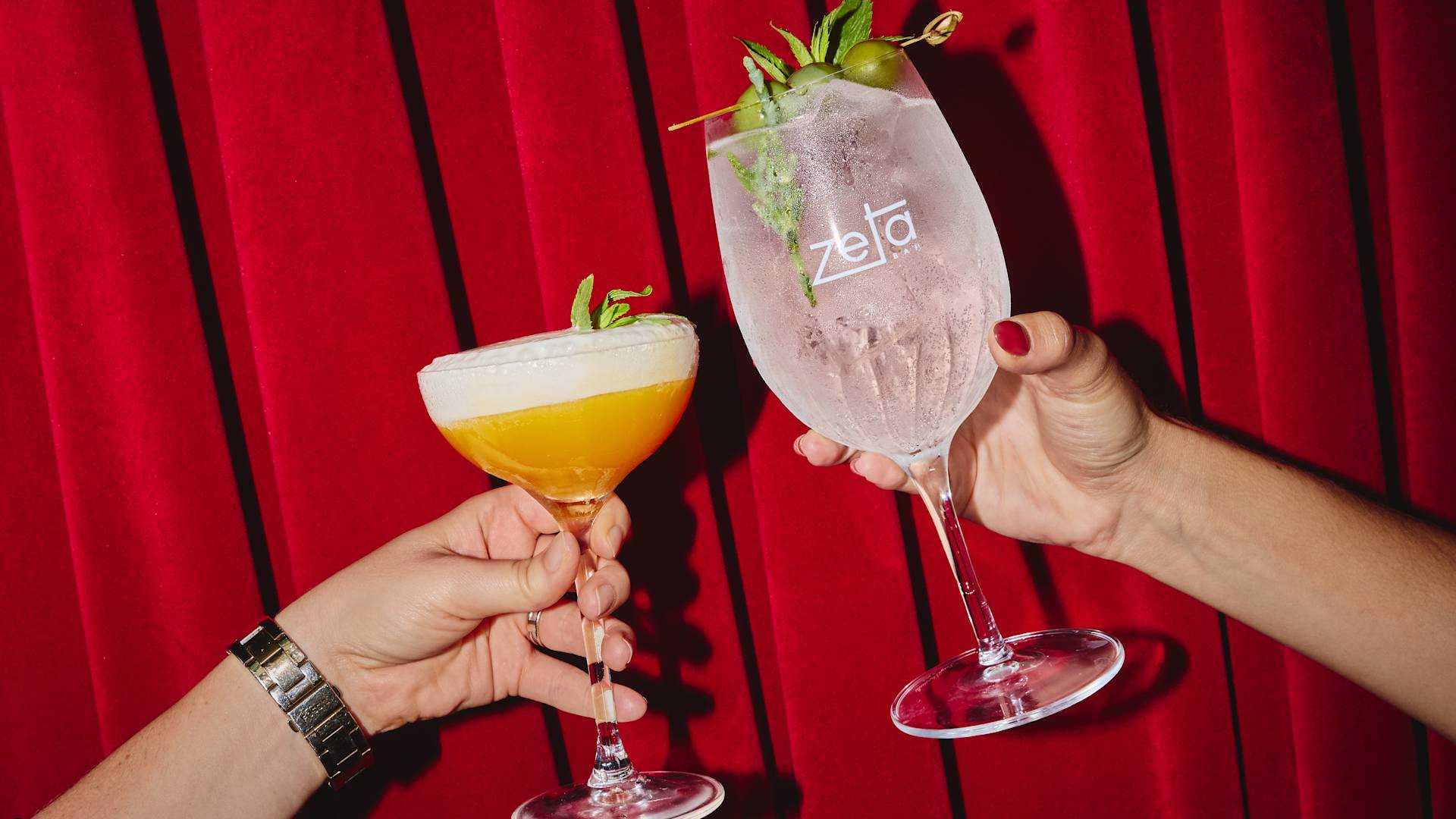 Cocktail glasses being held in Zeta Bar