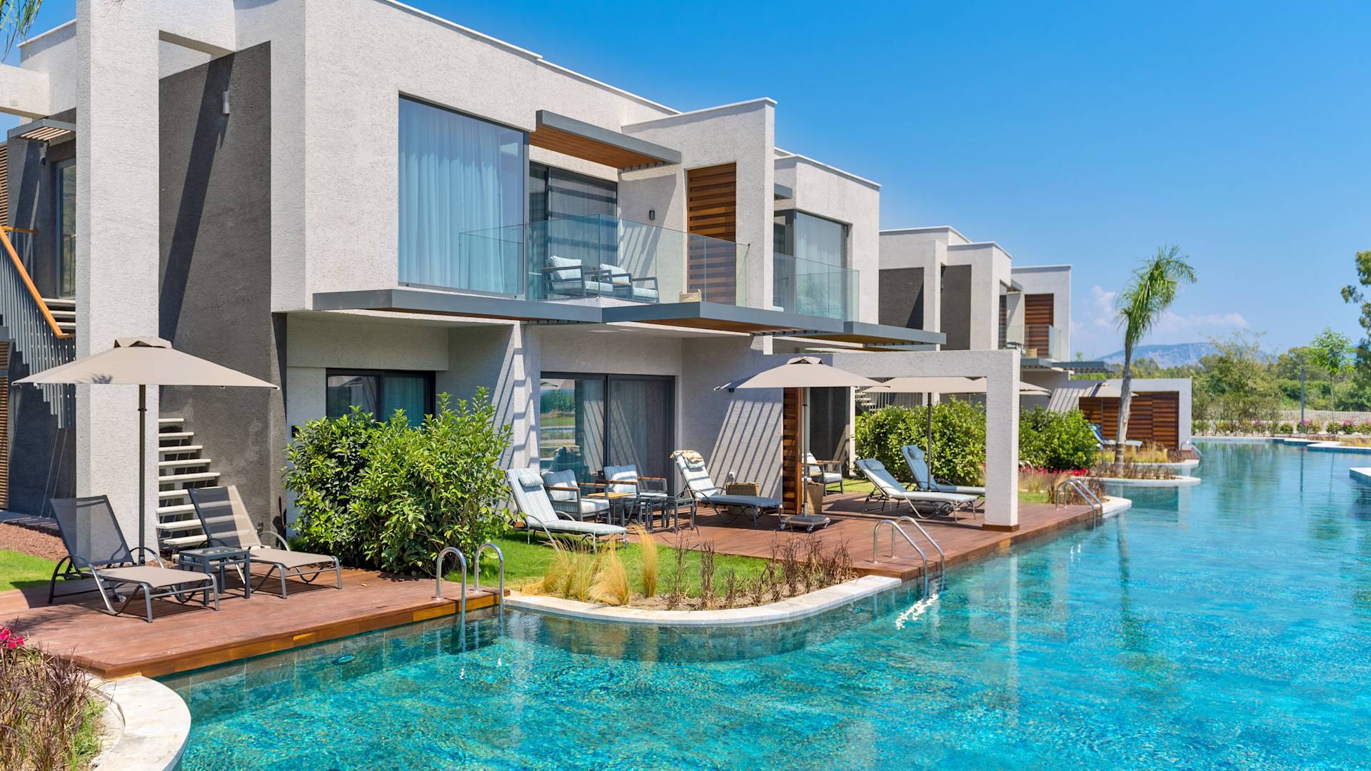 outdoor view of the pool at the lake house, lounge chairs, umbrellas