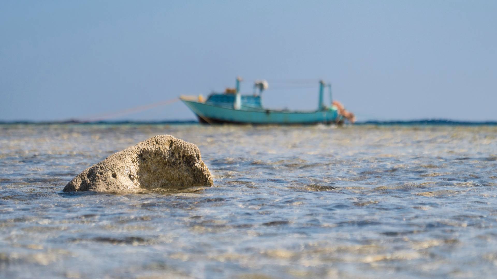 A boat cruises on the ocean in the distance