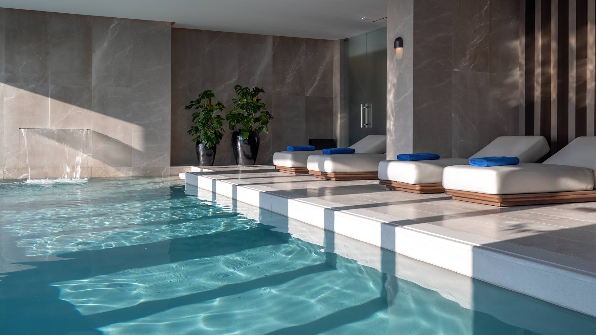 Aurora spa pool with four loungers and a waterfall.