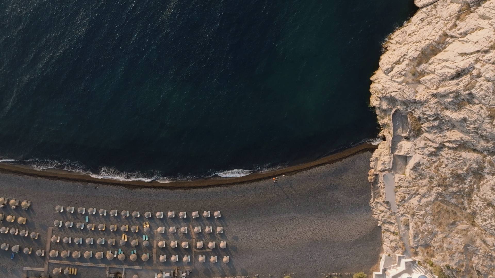 ภาพมุมสูงของชายหาดรีสอร์ทที่แสดงให้เห็นถึงหินตามแนวชายฝั่ง