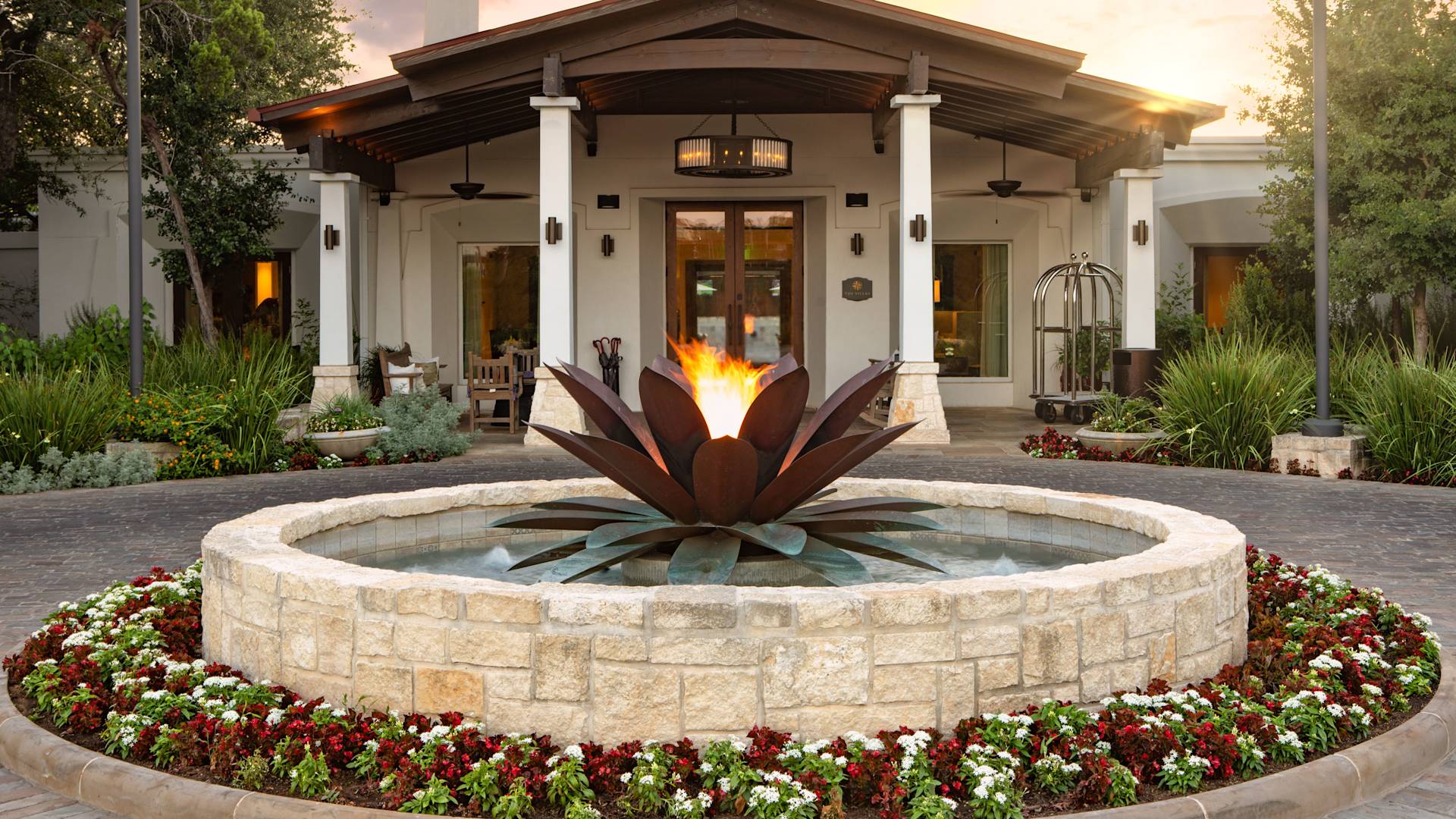 Water feature with large metal agave plant in the middle, in front of a villa on hotel grounds