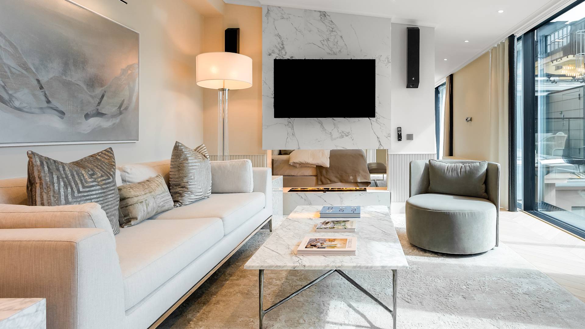 غرفة معيشة بها أريكة، ومقعد بذراعين، ومدفأة، وتلفزيون، وأبواب زجاجية منزلقة تؤدي إلى فناء