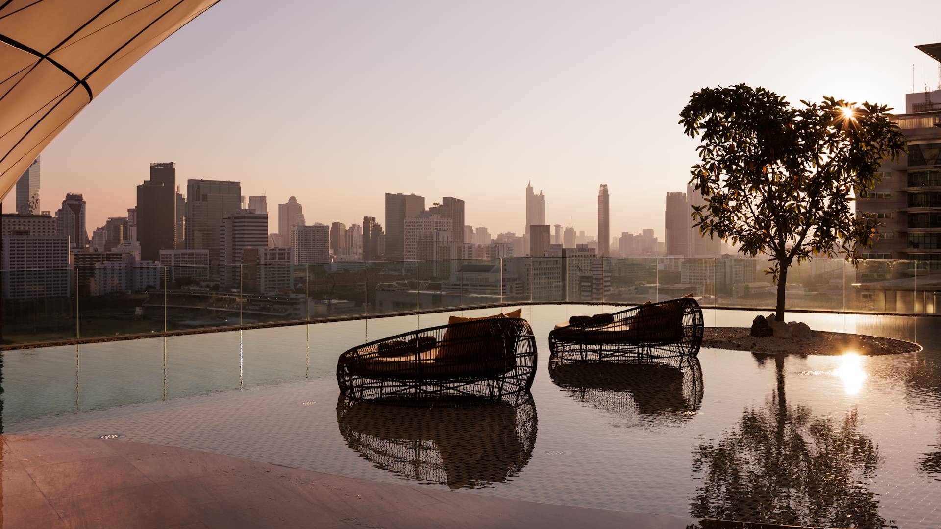 Outdoor Swimming Pool with Seating Are and City View at Sunset