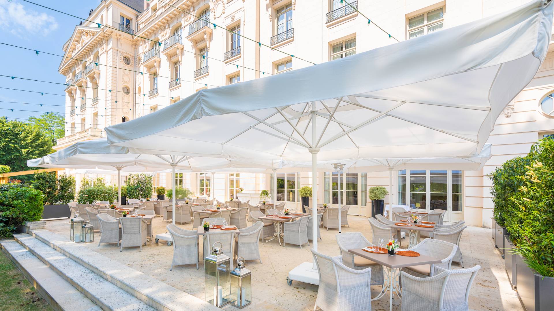 Výhled na terasu se stoly a židlemi pod deštník