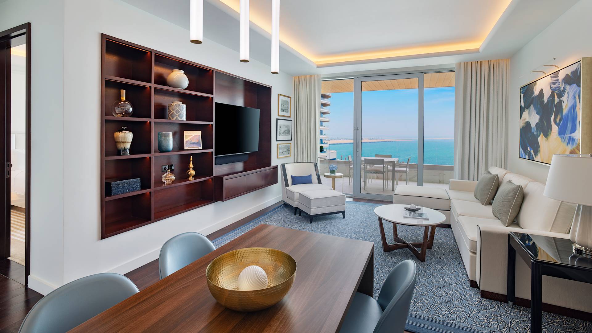 Lounge area with sofa, chair, balcony access and wall mounted TV