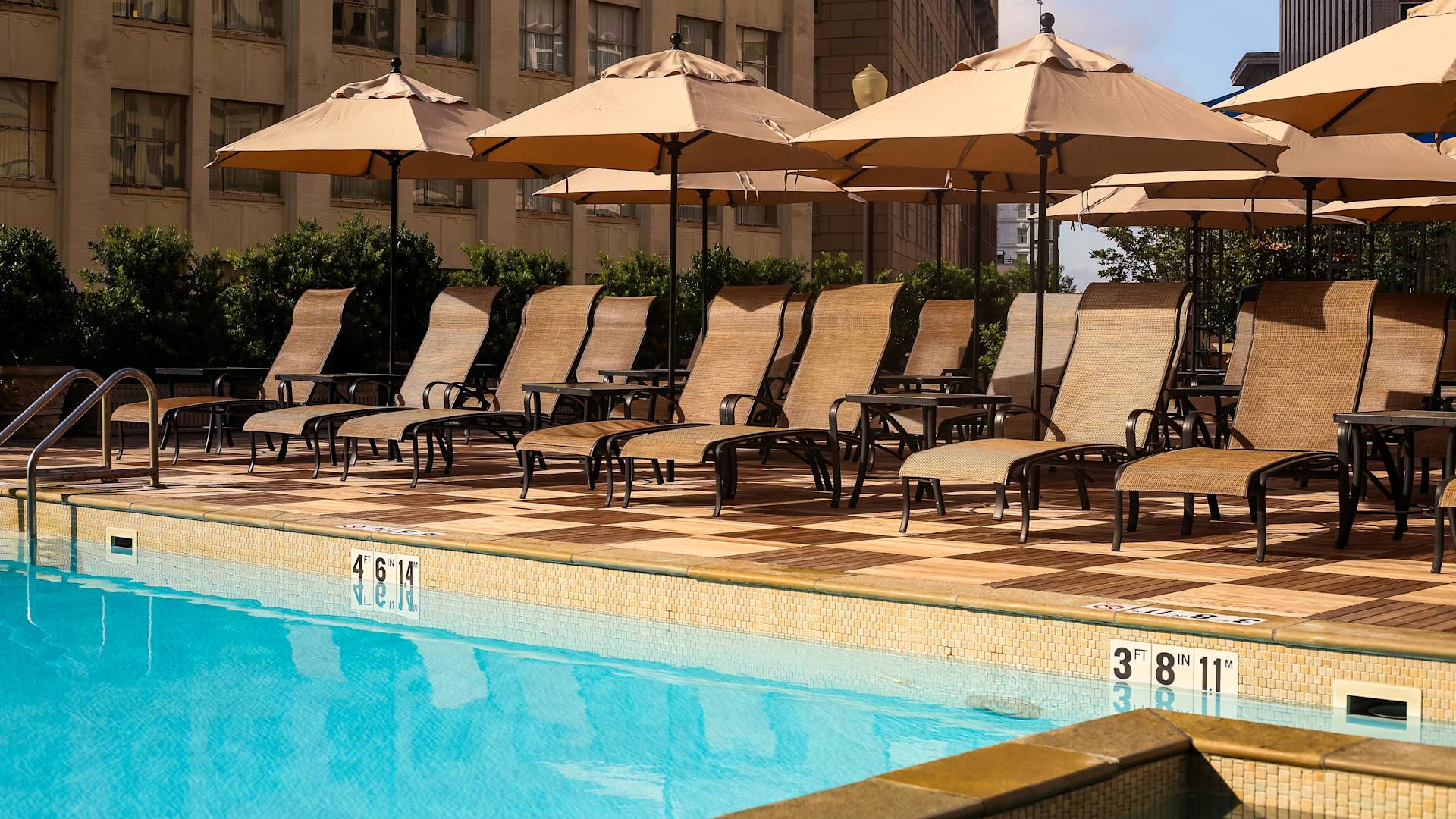 户外游泳池，配有遮阳伞下的躺椅