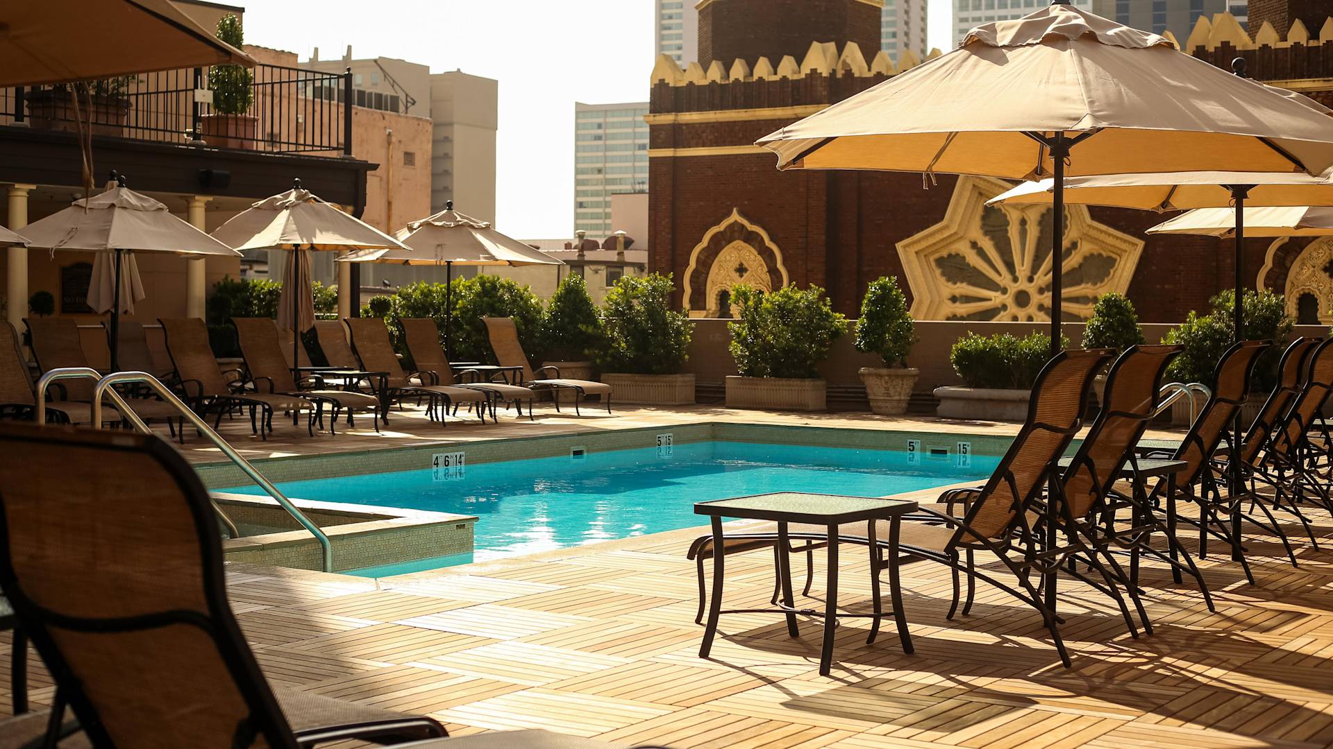 户外游泳池，配有遮阳伞下的躺椅