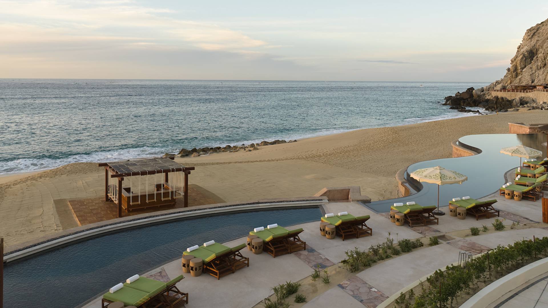 Amplia área de la piscina al aire libre con divanes y vista al mar