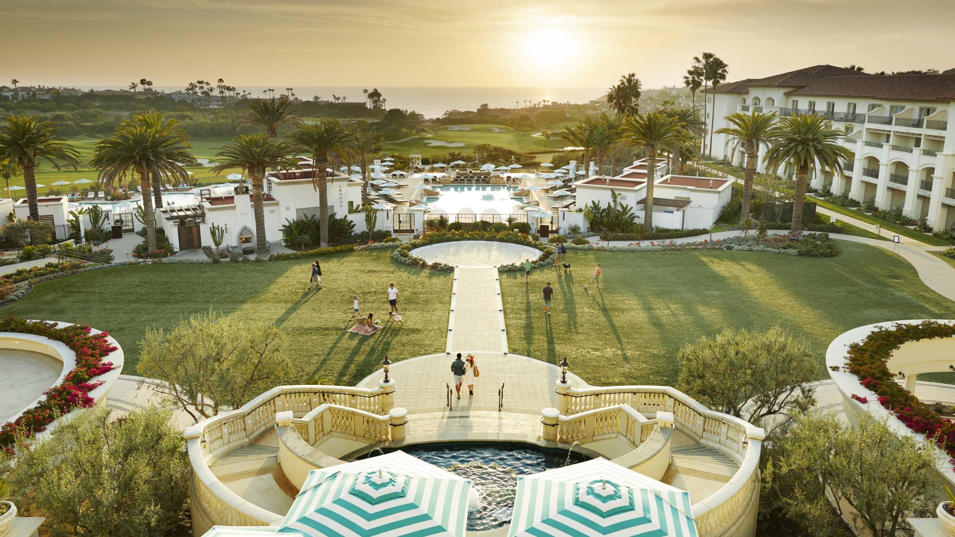 aerial view of hotel exterior and grounds with pools, view of golf course, and people walking