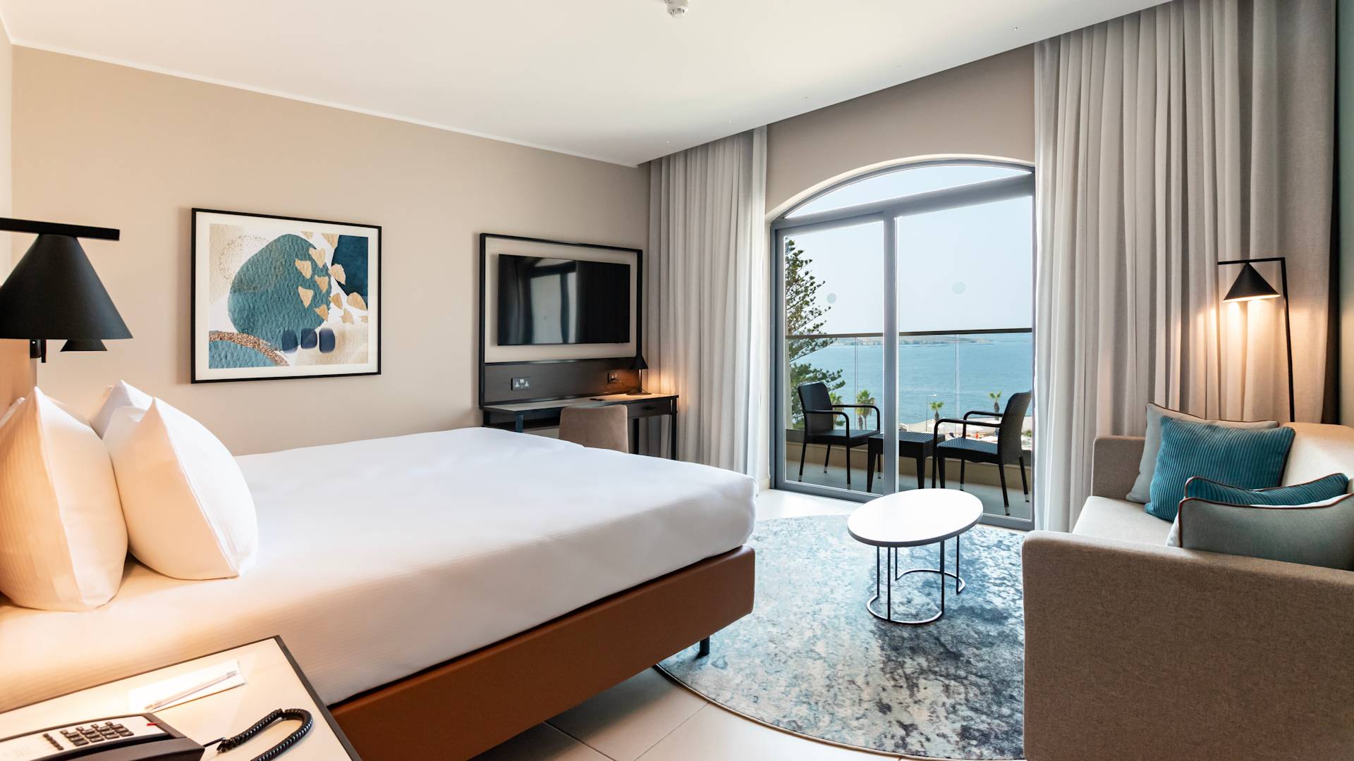 TV, kanepe ve masa bulunan yataklı oda