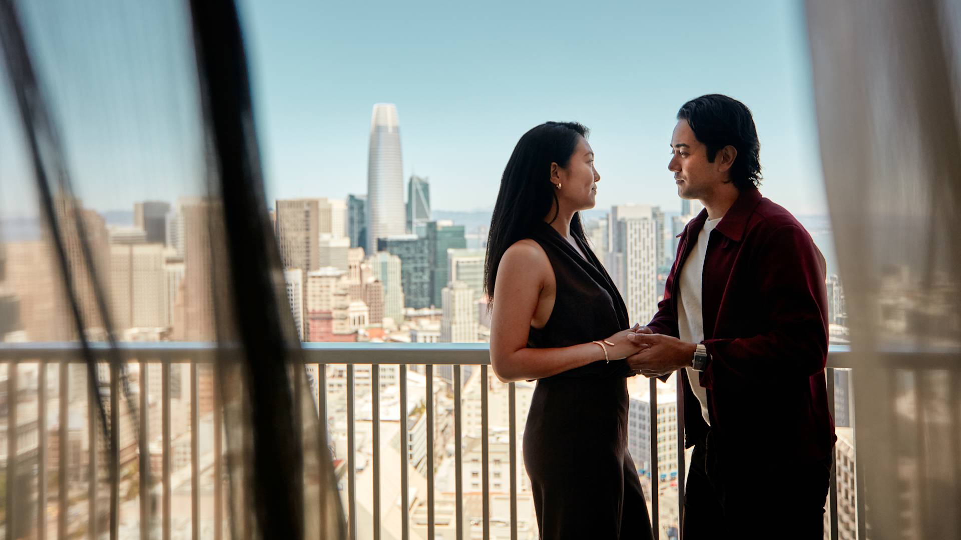 A couple enjoying views of the city from their suite balcony-transition