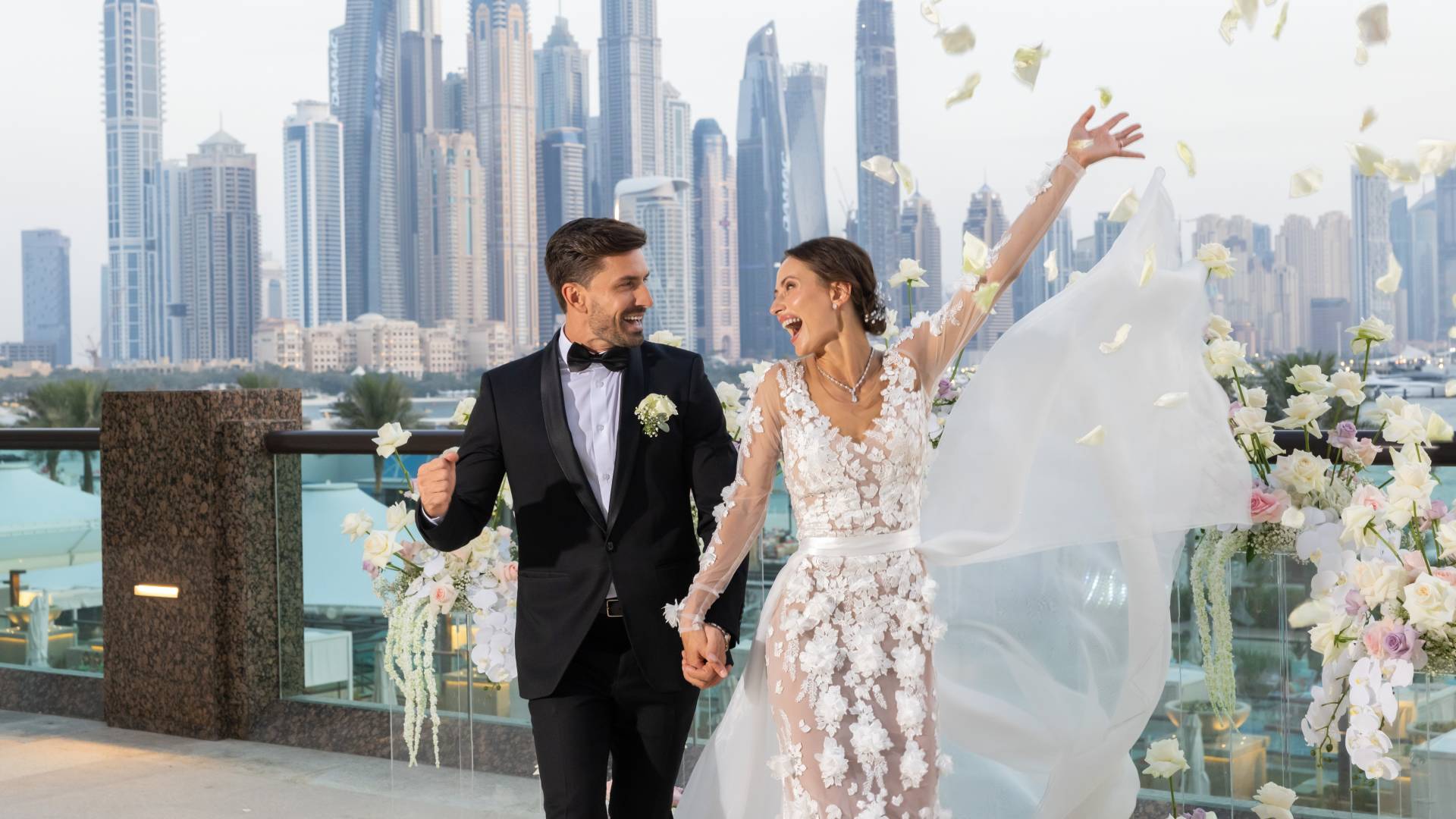 Bruiloftspaar viert met vrouw die bloemen in de lucht gooit