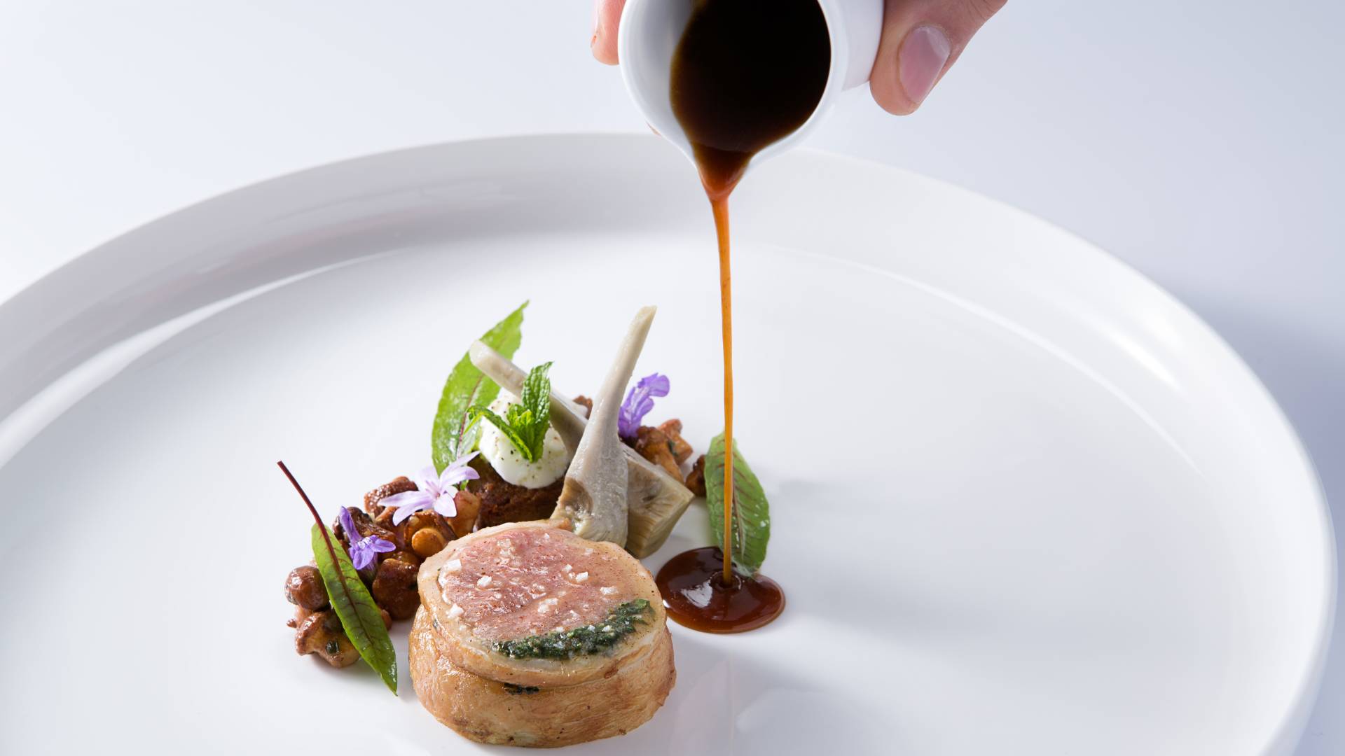 Plate of food with hand pouring sauce-transition