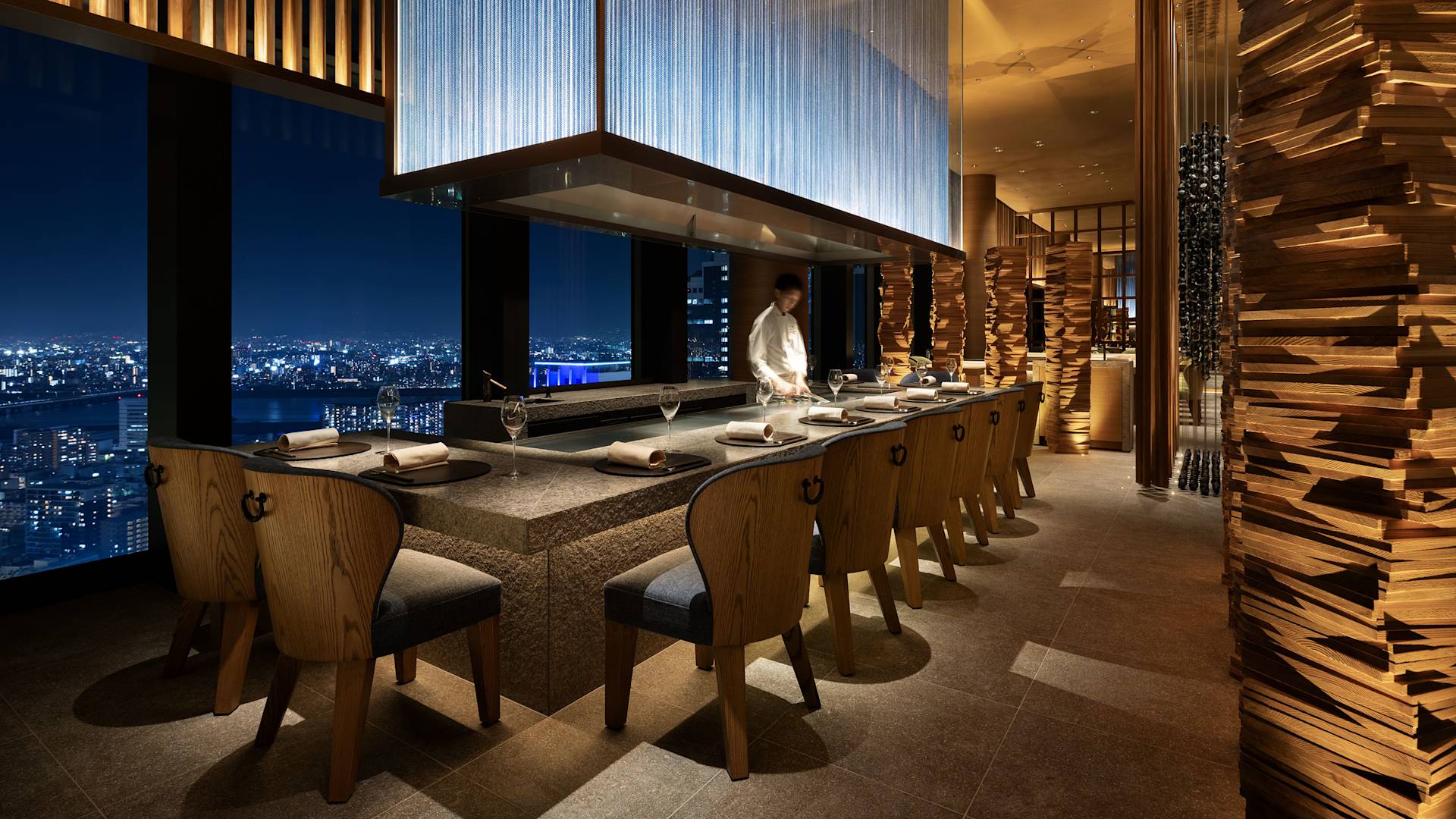 Chef stands at cooking station in front of dining tables at Waldorf Astoria Osaka-transition