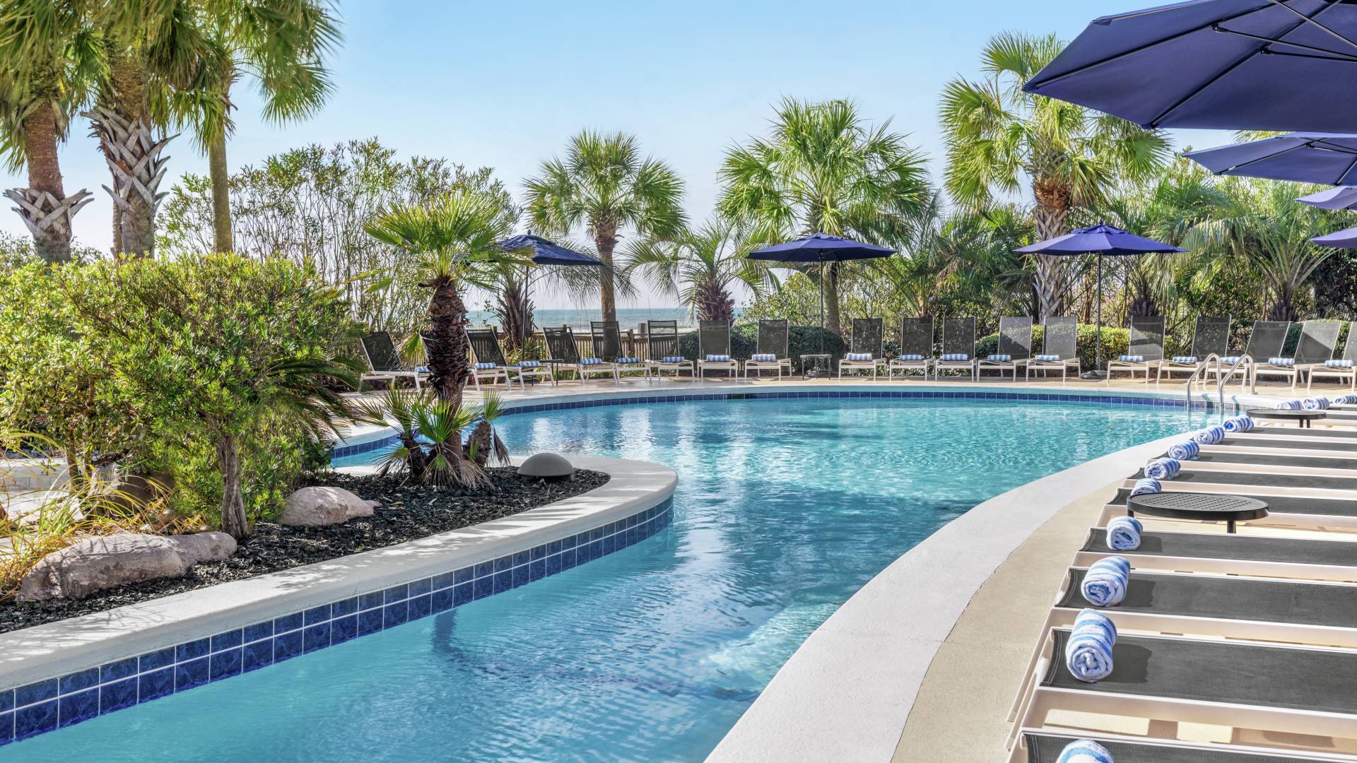 Beautiful outdoor pool featuring ample seating for guests to relax and ocean view.-transition