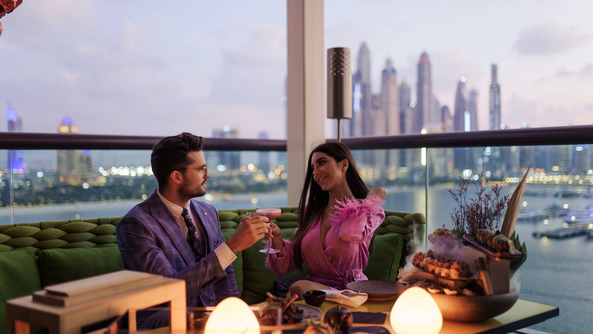 Couple of balcony with food platter and cityscape behind them