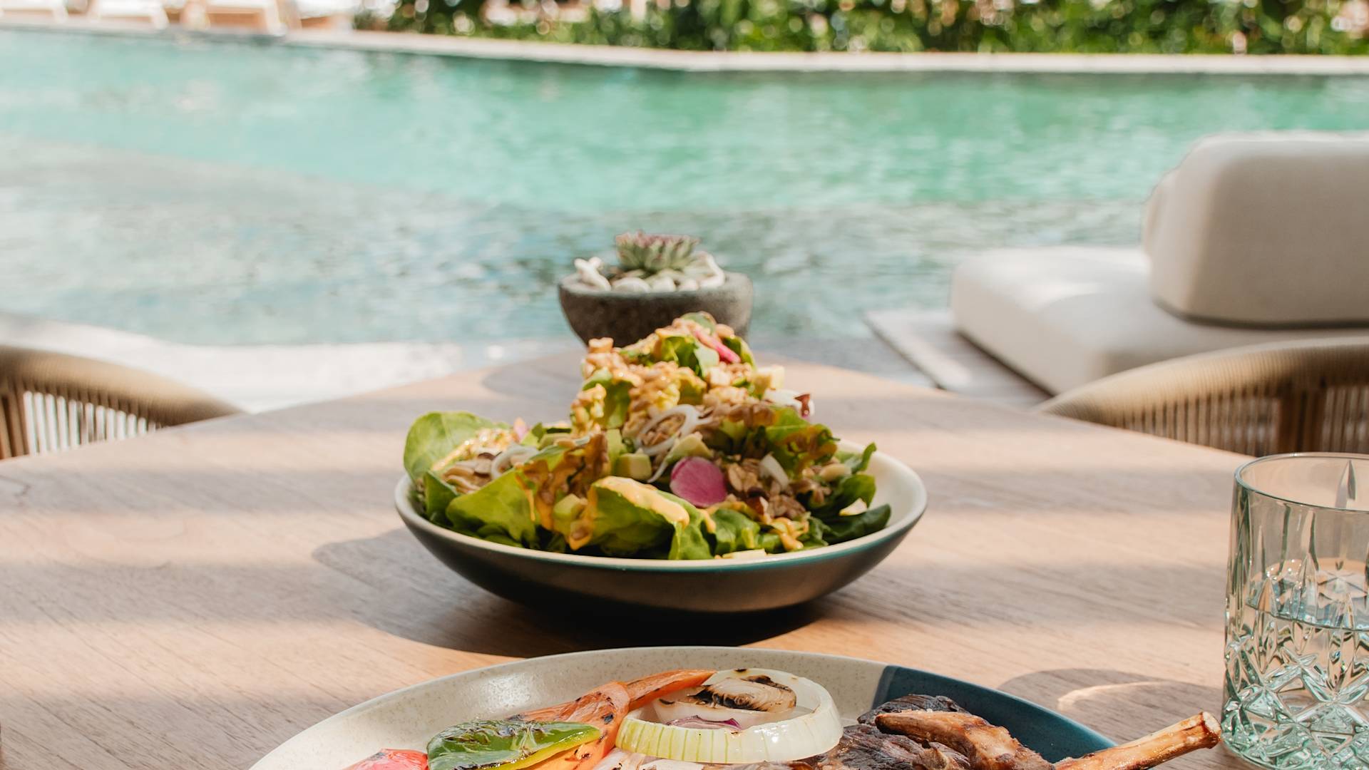 plated food dishes on table by outdoor pool-previous-transition