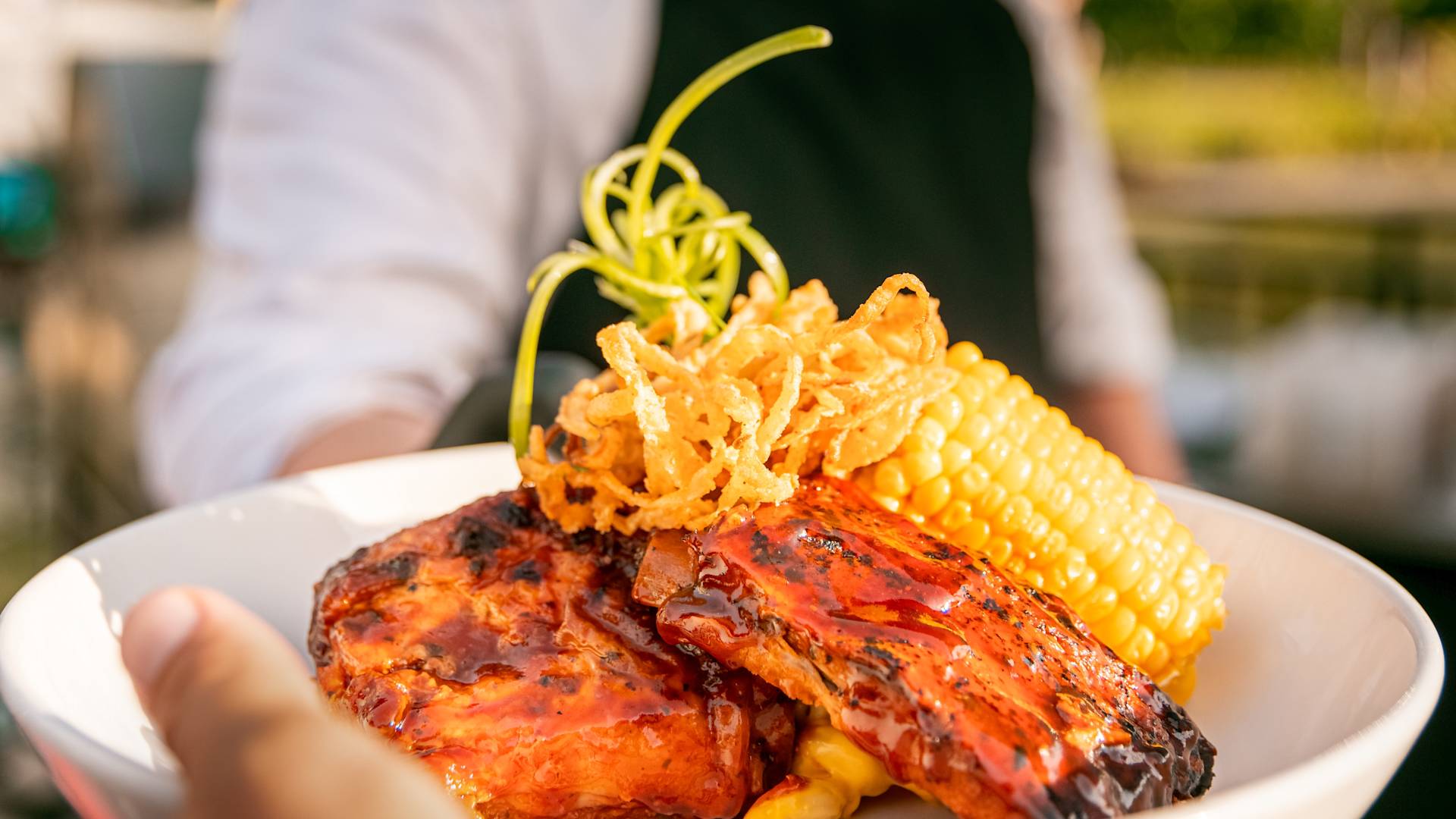 Person Holding a Plate with BBQ and Corn at Laguna Restaurant-transition