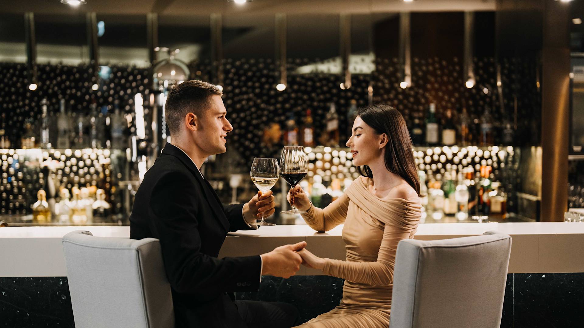 Couple holding hands at the bar and holding wine glasses-transition