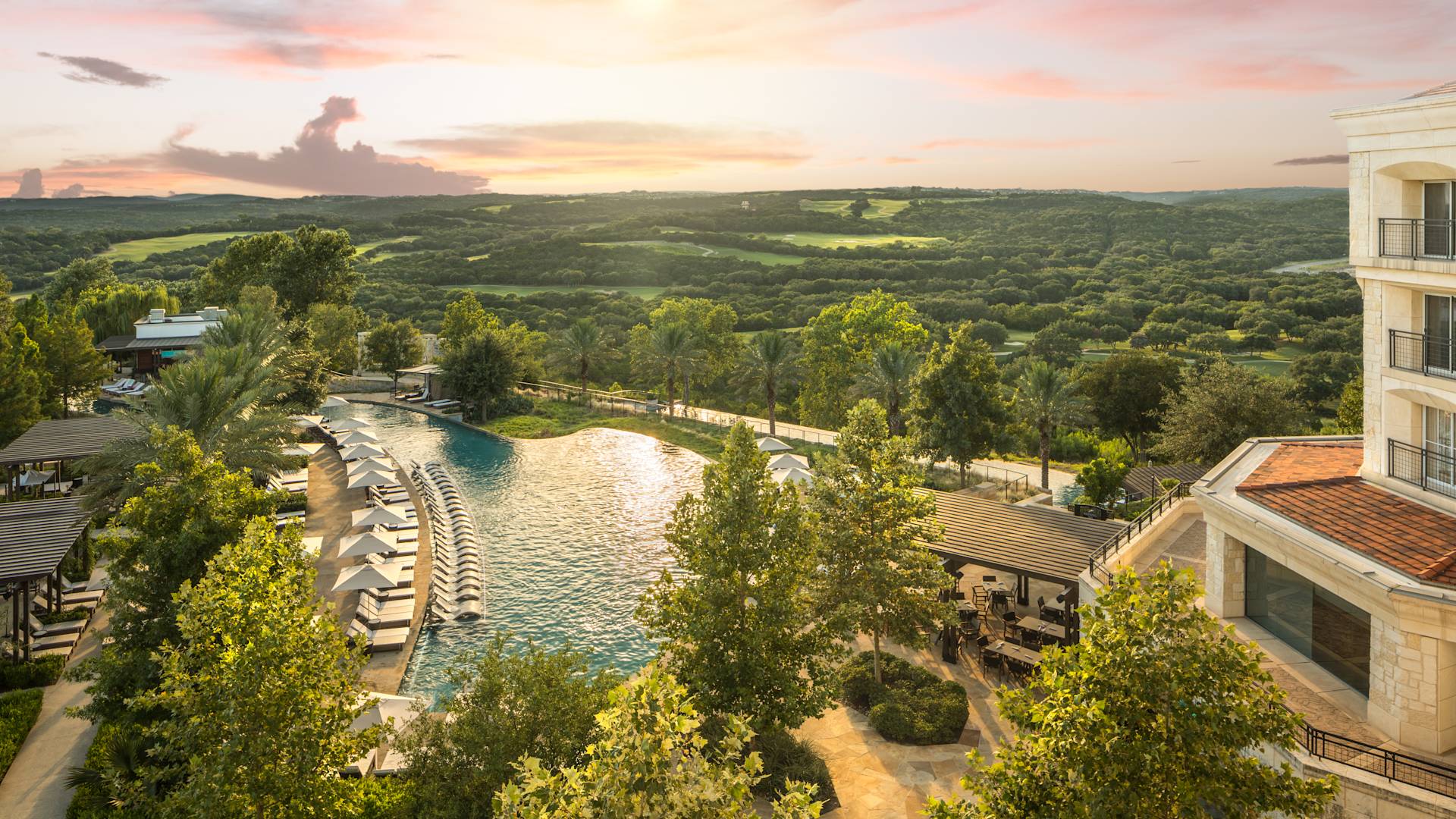 Hotel exterior, with outdoor pool with loungers and trees