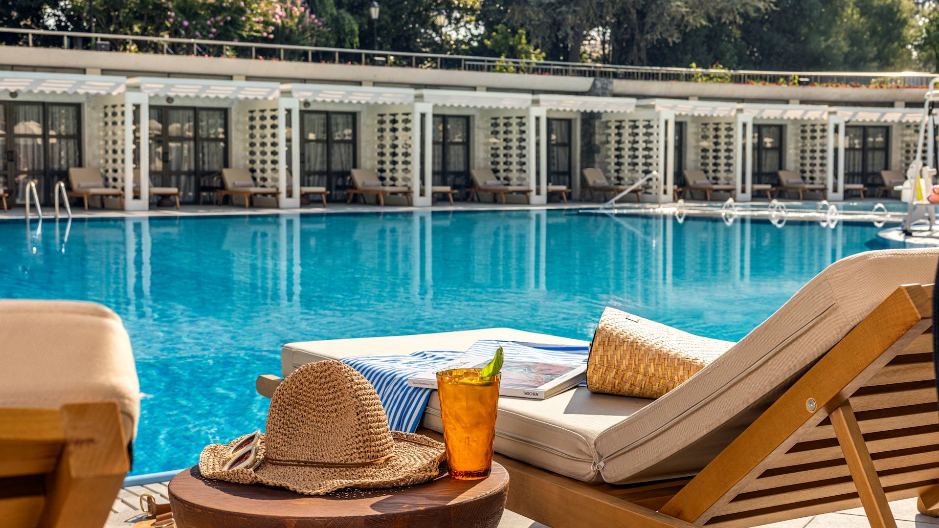 Hat and Drink auf einem Tisch neben einem Loungesessel im Außenpoolbereich