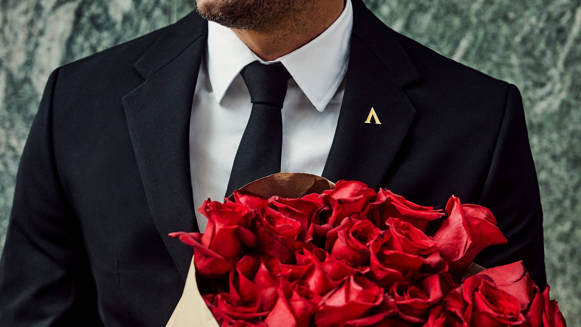 Un homme en costume tenant un bouquet de fleurs