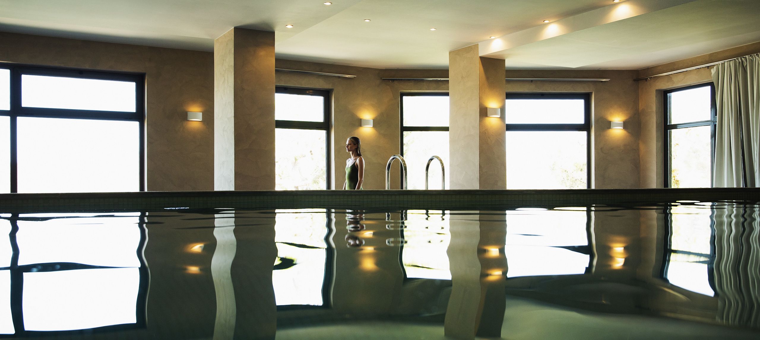 Indoor pool area with floor-to-ceiling windows showing an outdoor view.