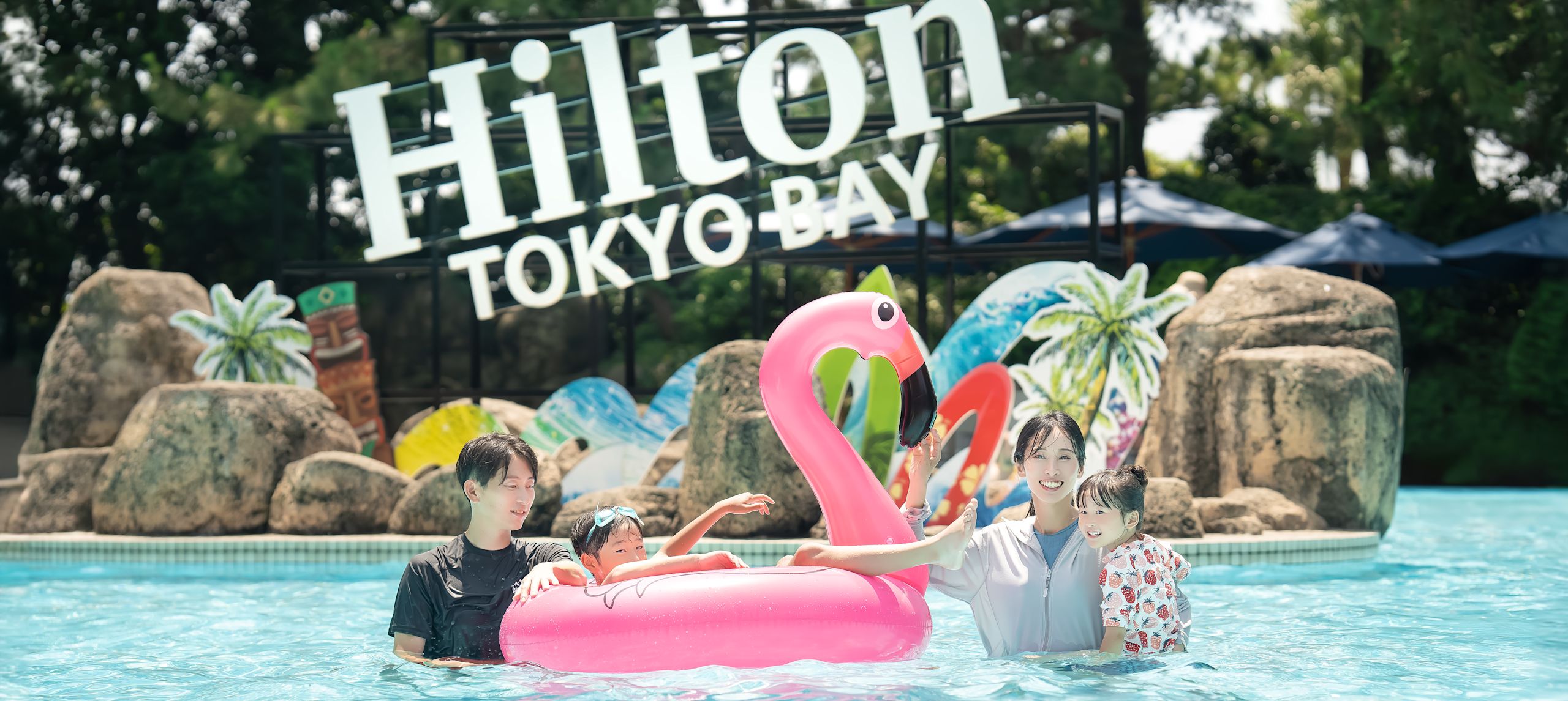Family looking at camera with flamingo floating device