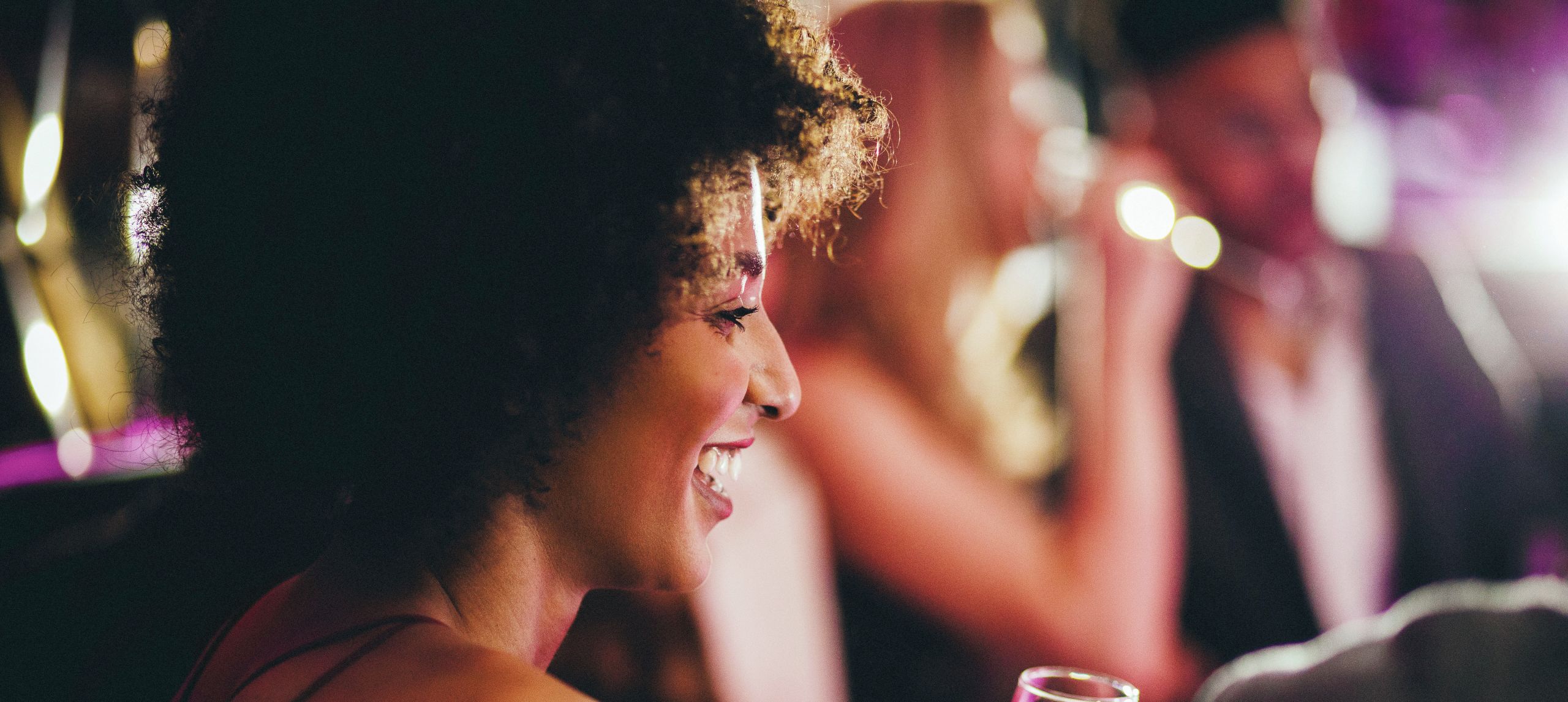 Close up shot of a woman enjoying a glass of champagne as she parties in a nightclub with her friends.