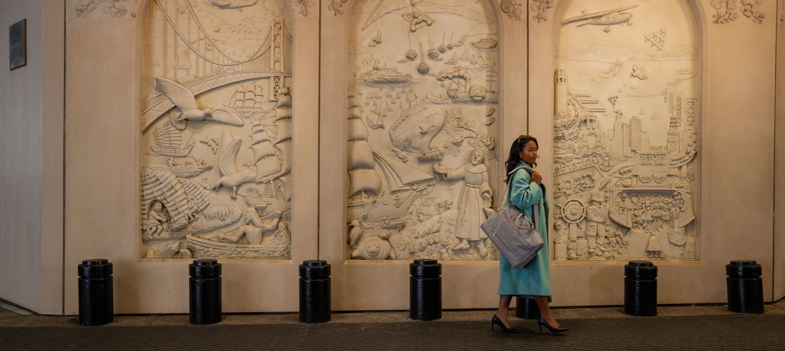 A woman walking on hotel exterior with designs on panels