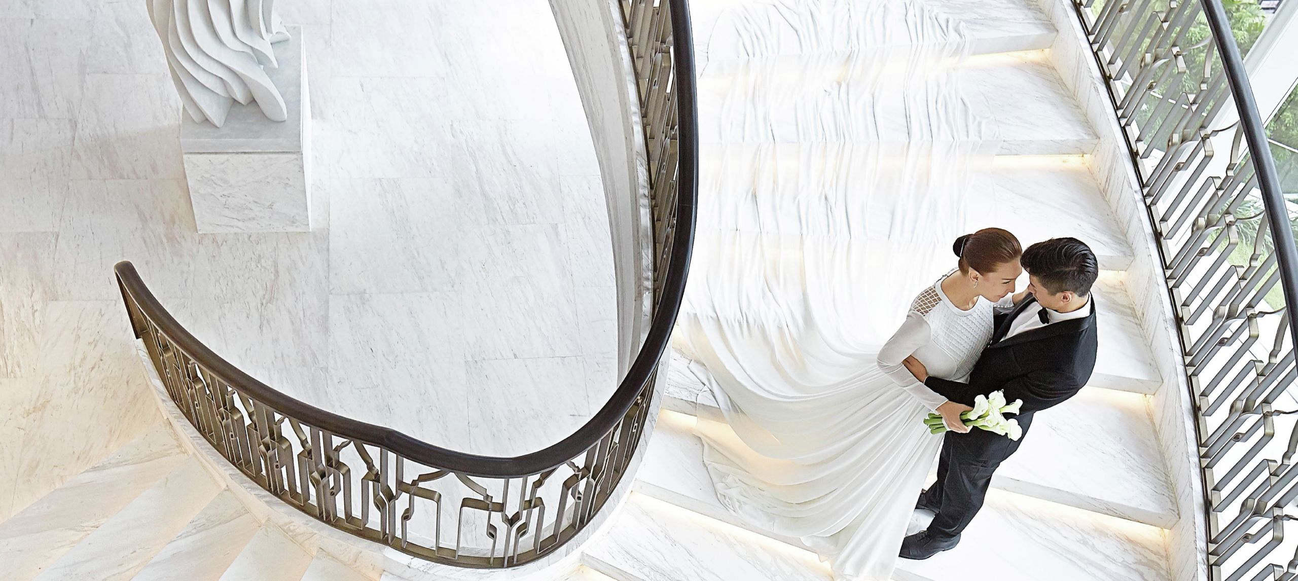 A wedding couple holding each other on the spiral staircase