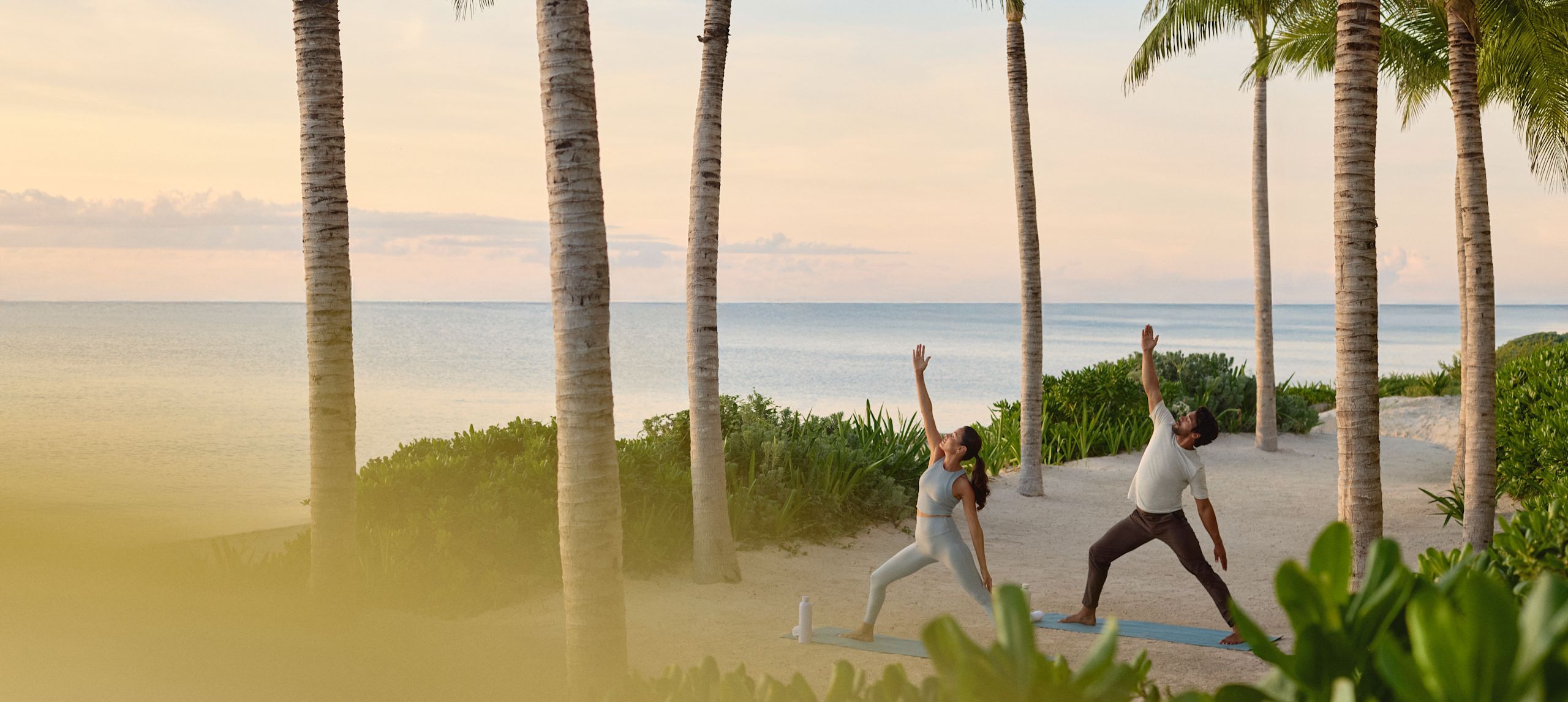 Bărbat și femeie făcând yoga în timpul unei călătorii pe plajă