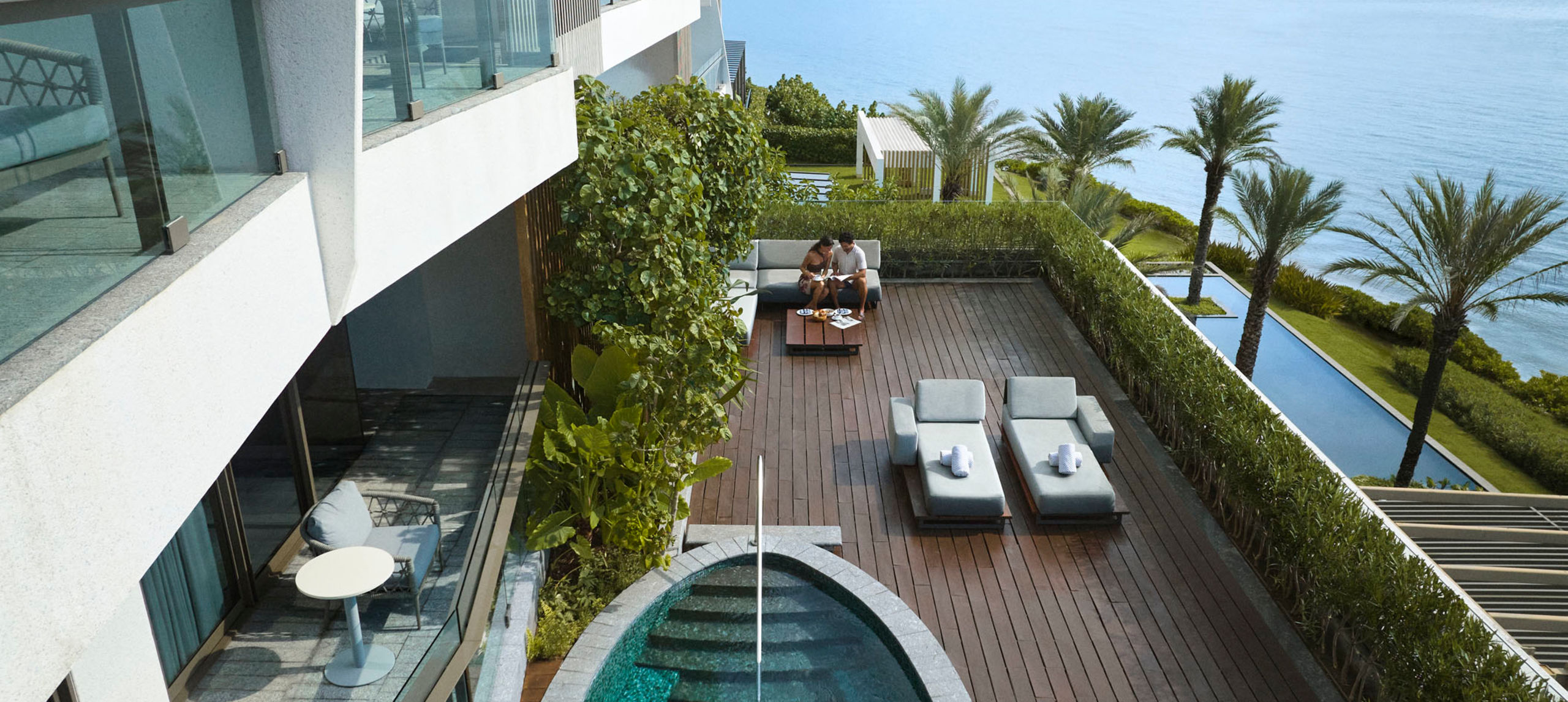 Man and woman relaxing on the patio of their suite with private pool-next-transition
