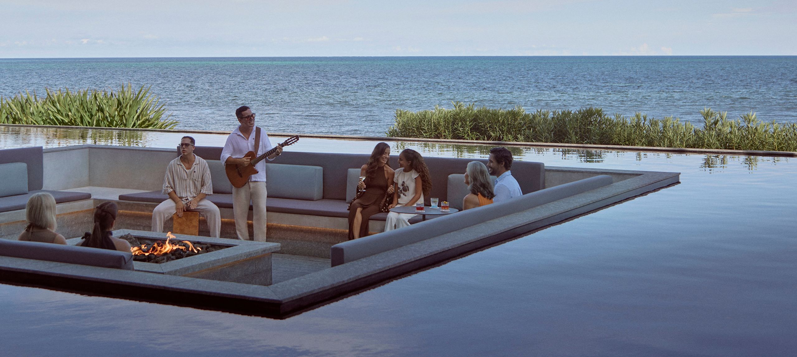 Hotel guests sitting by pool in the evening listening to guitar entertainment-next-transition
