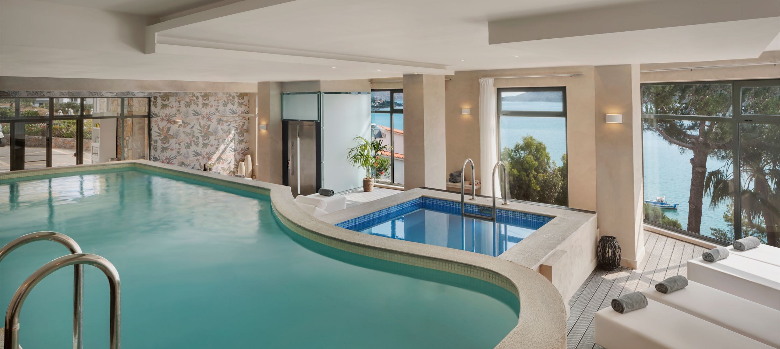 Indoor pool with a smaller adjacent pool and floor-to-ceiling picture windows with ocean views.