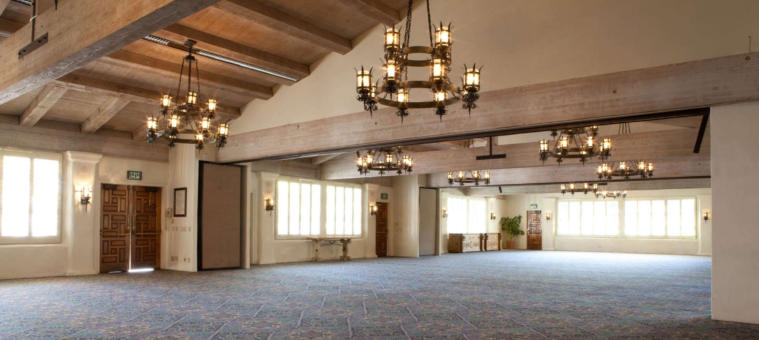 Amplia sala de reuniones con chandeliers y vigas de madera