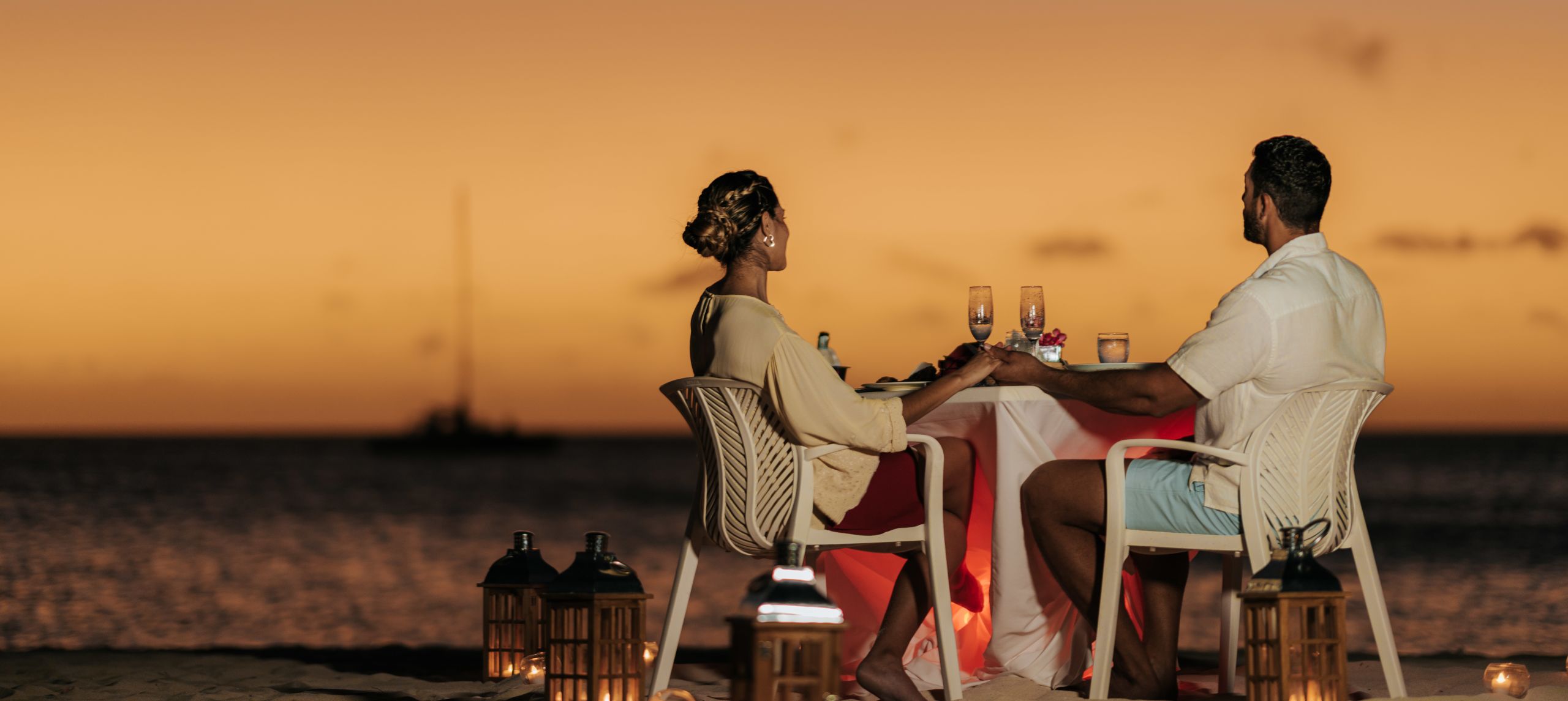 Couple dining on the beach watching sunset