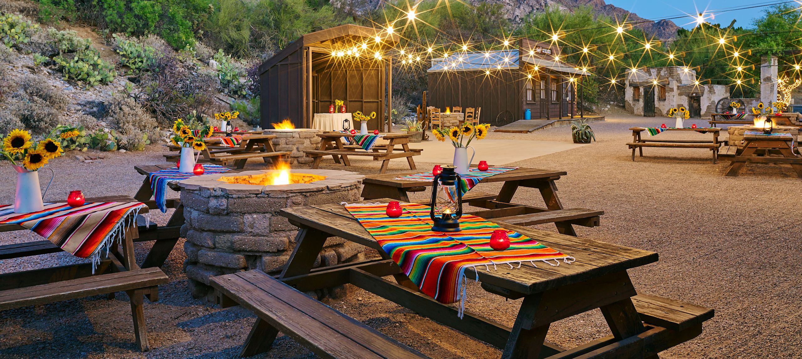 Last Territory Meeting Area at Night with Lights, Tables, Chairs, and Firepit Outdoor