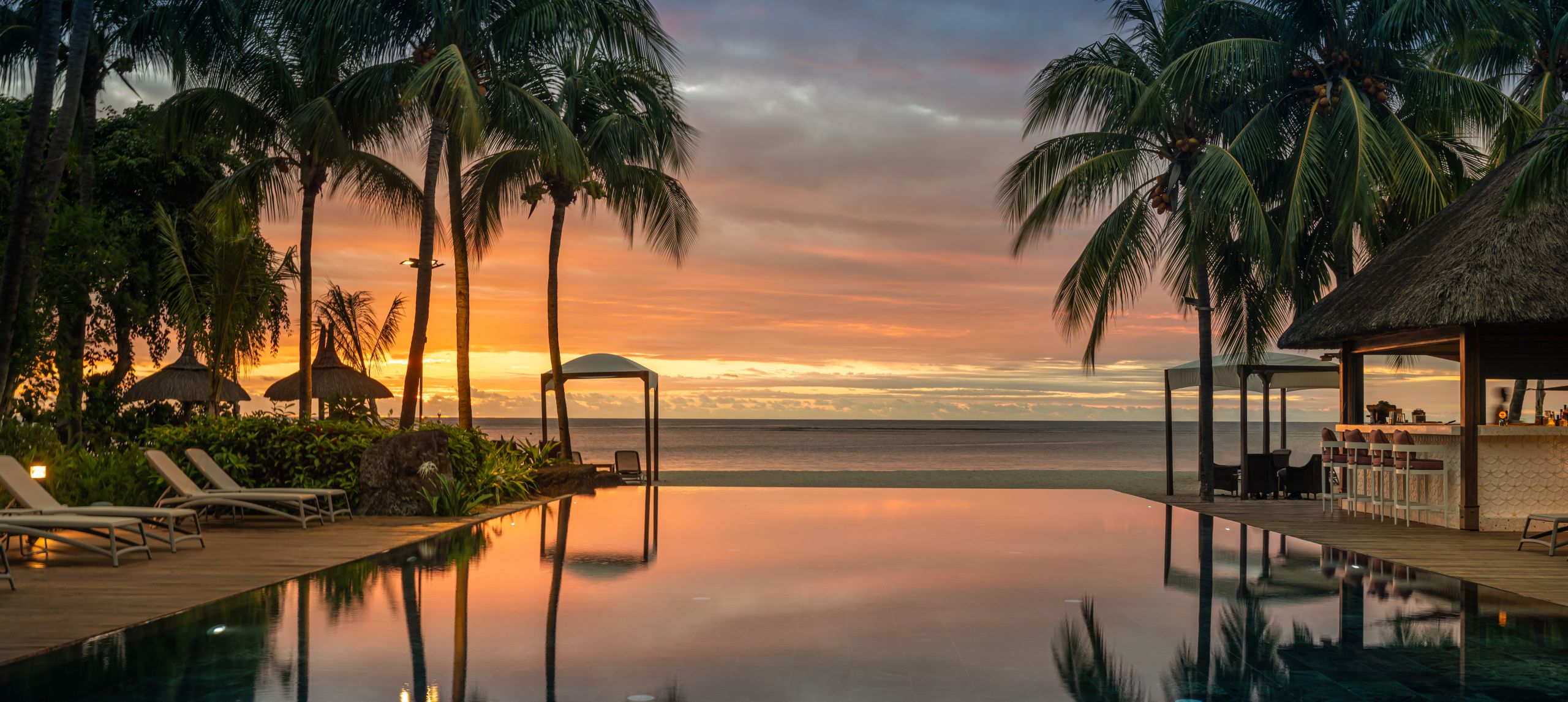 Piscine extérieure avec vue sur le coucher de soleil à travers les arbres