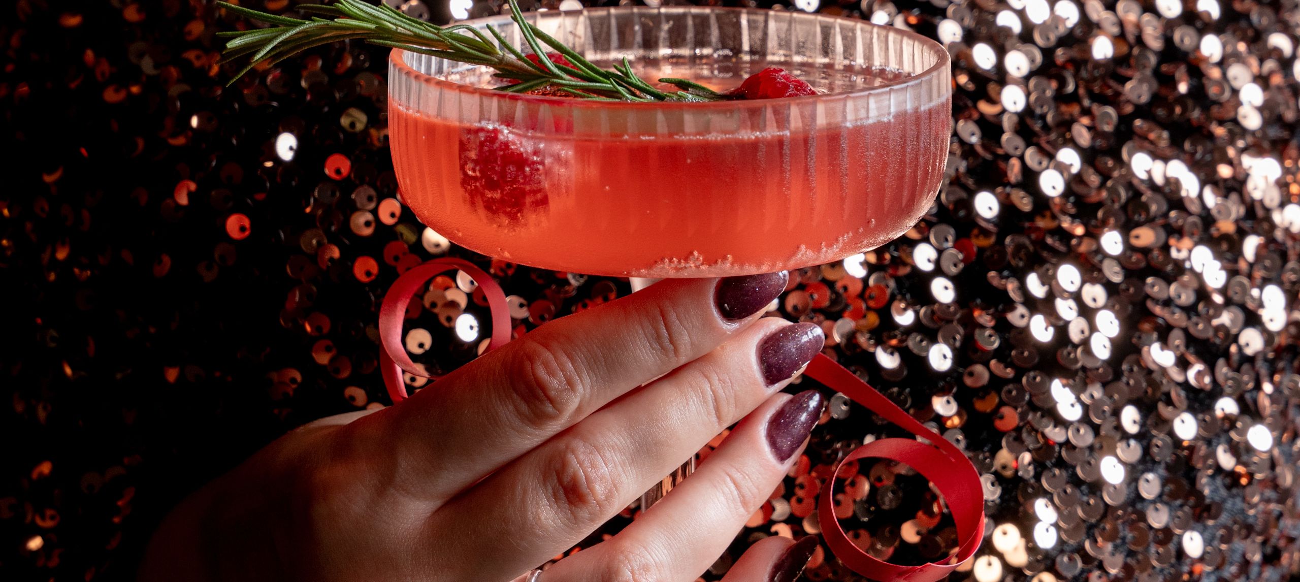 The Cortland Bar, guest holding a festive cocktail with raspberries and rosemary