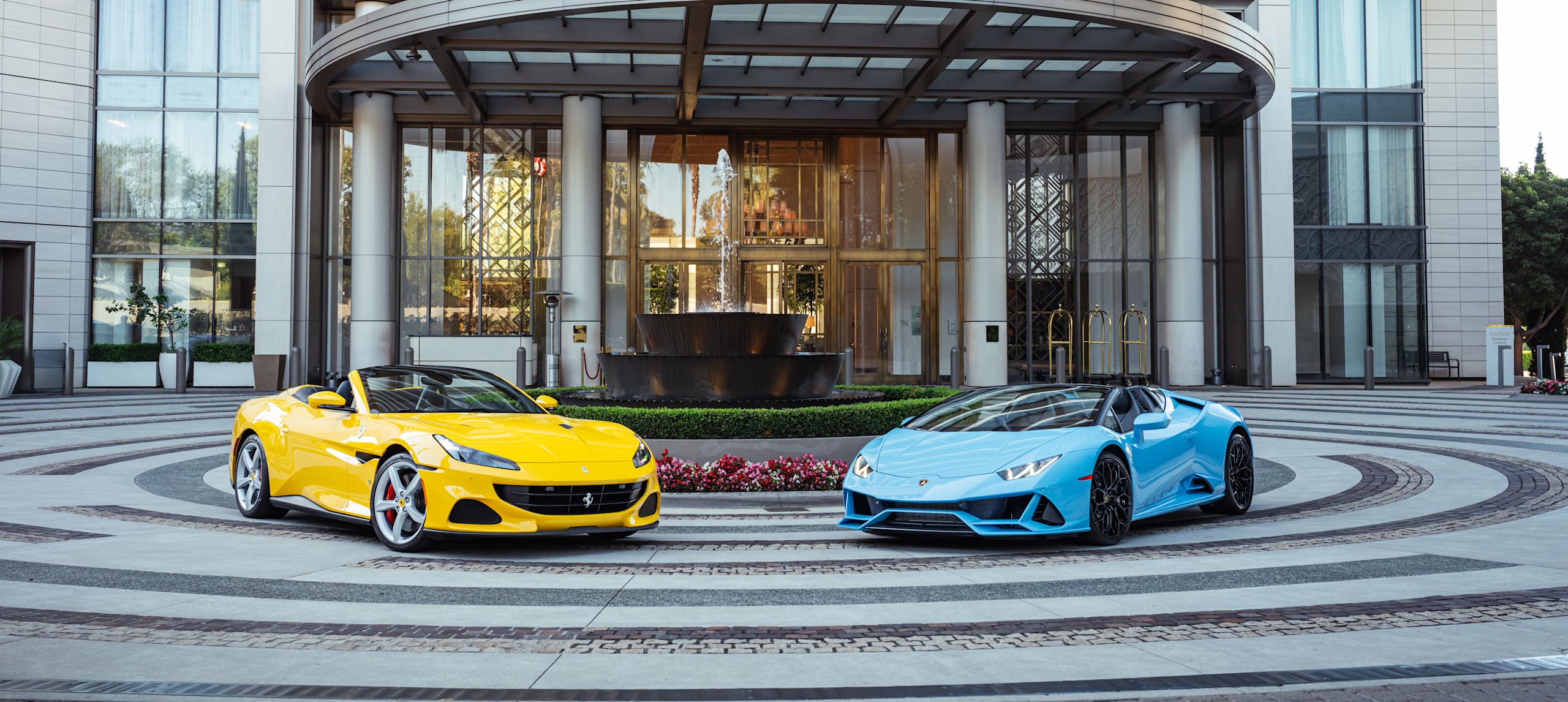 hotel exterior, yellow and blue car in front of the building and water fountain