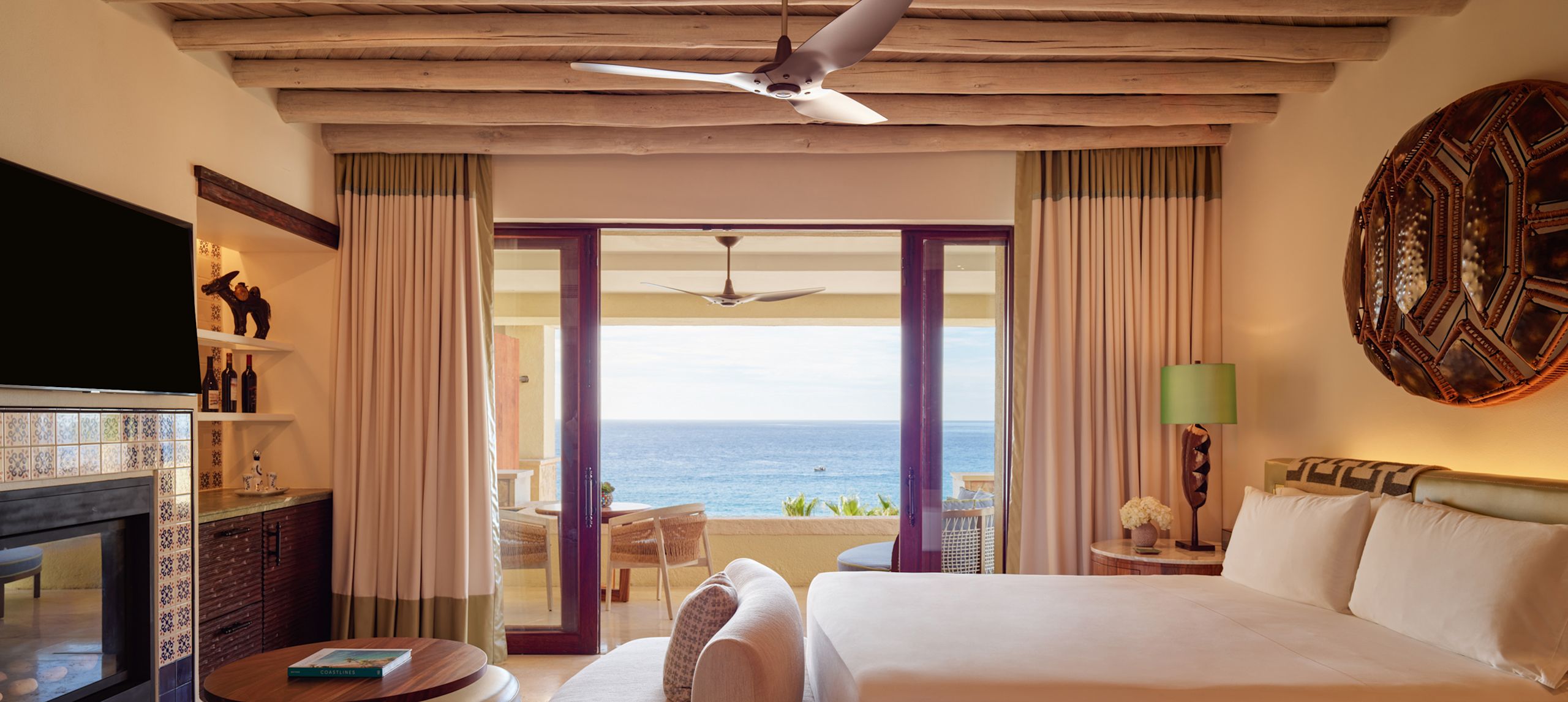 Cama amplia y televisor en una habitación con vista al mar desde el patio