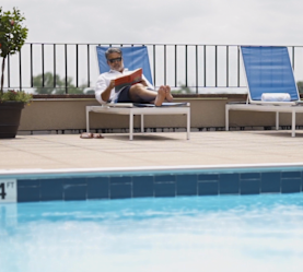 a Man Reading while Laying in a Lounge Chair in Outdoor Pool Area